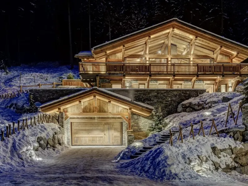 Chalet Azurite glowing gold against deep blue snow at night, Les Nants, Chamonix