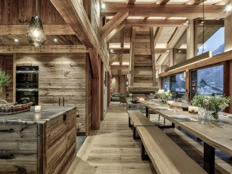 The open kitchen and long dining table at Chalet Alaska, under a beamed timber ceiling
