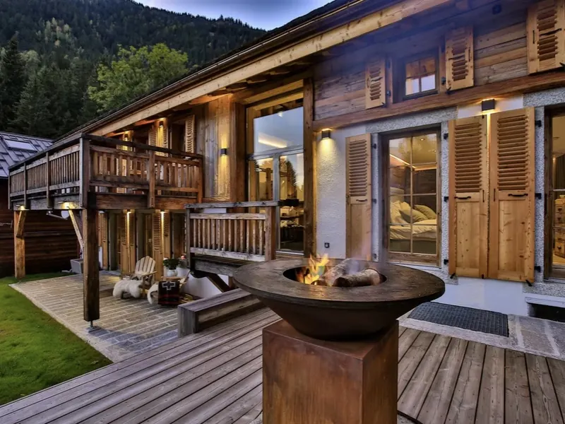 The terrace at Le Moulin, a fire bowl burning beside carved timber shutters, Les Tines