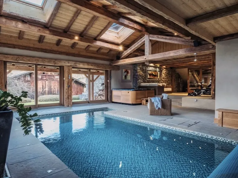 The indoor pool at La Ferme de l'Aberau, under a glazed roof and old farmhouse beams