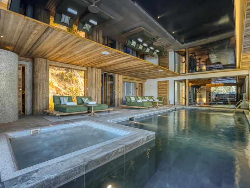 The indoor pool at Chalet Eagle, glass walls opening to the snow outside, Megève