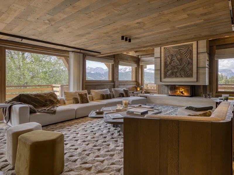 The salon at Chalet Quartz, a fire and deep sofas framed by windows onto the mountains, Megève