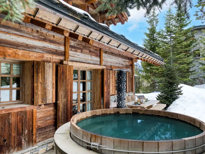 The nordic bath outside Chalet Ami, steaming beside weathered timber and deep snow, Courchevel