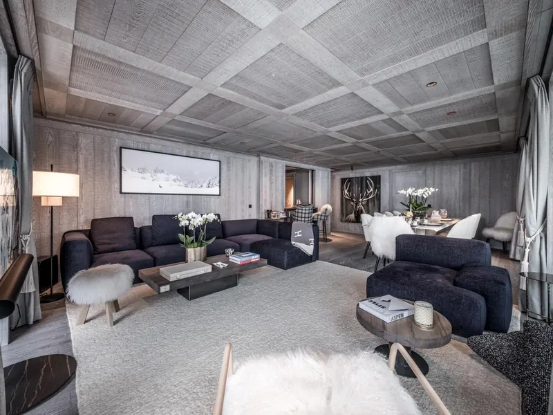The salon of Apartment Grey Garden, pale stone and soft wool under a panelled ceiling, Courchevel