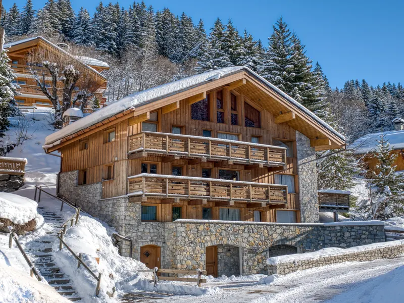 Chalet Zybeline in fresh snow, stone and timber balconies against dark pines, Méribel