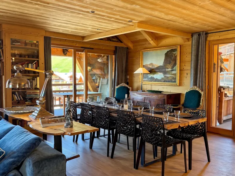 The dining and living room of Apartment Eden Rock, timber walls hung with paintings, L'Alpe d'Huez